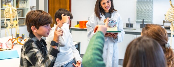Professeur de Science expliquant l'anatomie de l'oeil humain à des lycéens utilisant un mannequin lors d'une leçon de biologie dans le laboratoire de l'école
