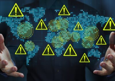 Homme d'affaires tenant une carte du monde et des icônes triangulaires d'avertissement.
