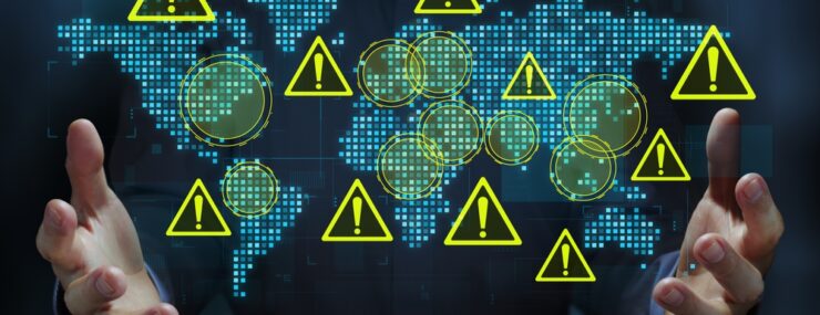 Homme d'affaires tenant une carte du monde et des icônes triangulaires d'avertissement.
