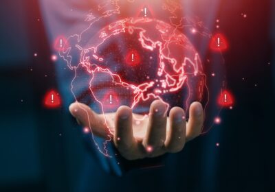 Concept d'alerte mondiale sur les risques et les crises avec main d'oeuvre tenant une carte numérique du monde, montrant les signaux d'alerte, les menaces mondiales et la gestion des risques dans un environnement commercial international.