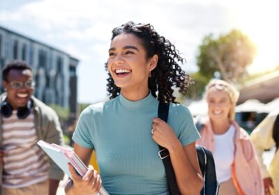 Marcher, heureux et fille avec des amis à l'université pour apprendre, se lier et parler avec plaisir. Personnes, école et groupe d'étudiants de la gén z qui font des trajets en plein air prêts pour l'éducation sur le campus universitaire.