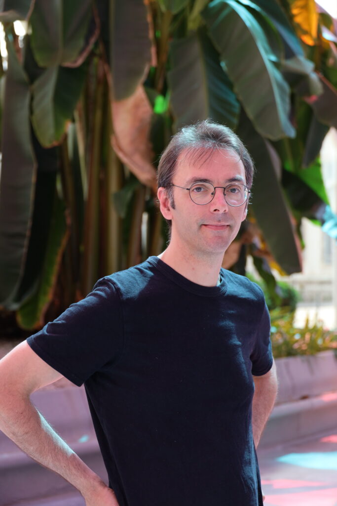 Photo portrait d'un homme dans la galerie du campus Artem à Nancy avec un arbre au fond